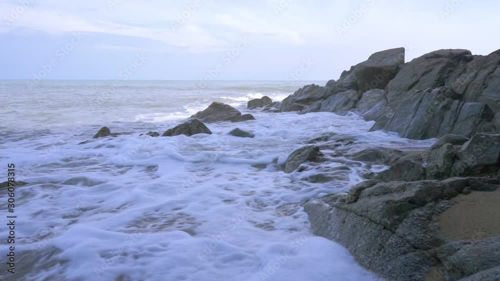 The morning sea had water waves breaking into the sandy beach with many rocks. The morning sea had water waves breaking into the sandy beach with many rocks.