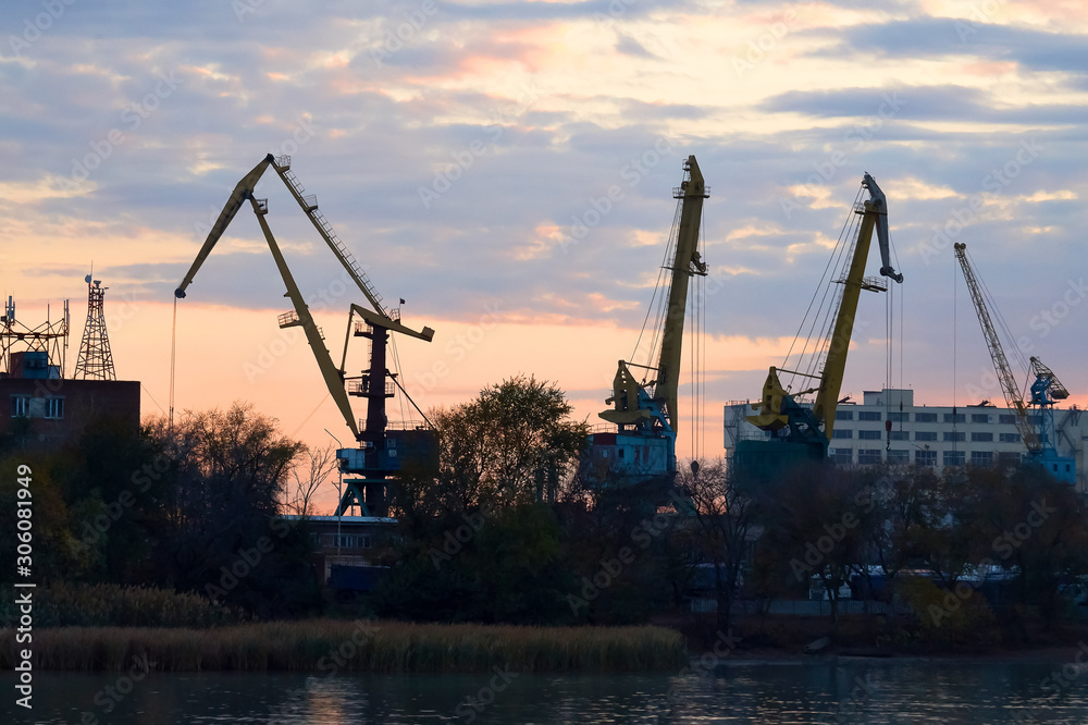 Harbor cranes craned their necks against the beautiful multicolored evening sky . Sunset in the port. Landscape. Harbor cranes craned their necks against the beautiful multicolored evening sky . Sunset in the port. Landscape.