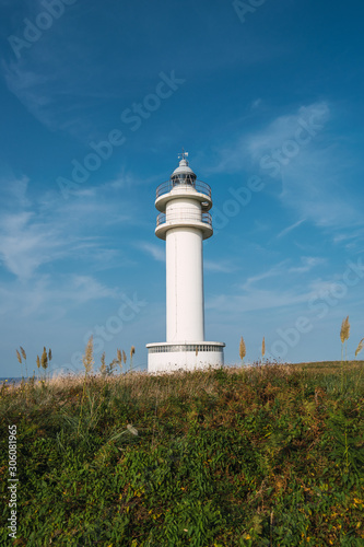Old lighthouse tower standing on hill in summer