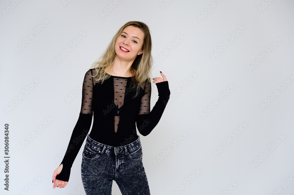 Concept of a woman talking to the camera. A photo of a pretty smiling girl with long beautiful curly hair in a black T-shirt on a white background is standing right in front of the camera. Concept of a woman talking to the camera. A photo of a pretty smiling girl with long beautiful curly hair in a black T-shirt on a white background is standing right in front of the camera.