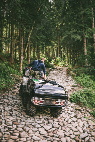 man on all-terrain vehicle ride by stone trail in forest