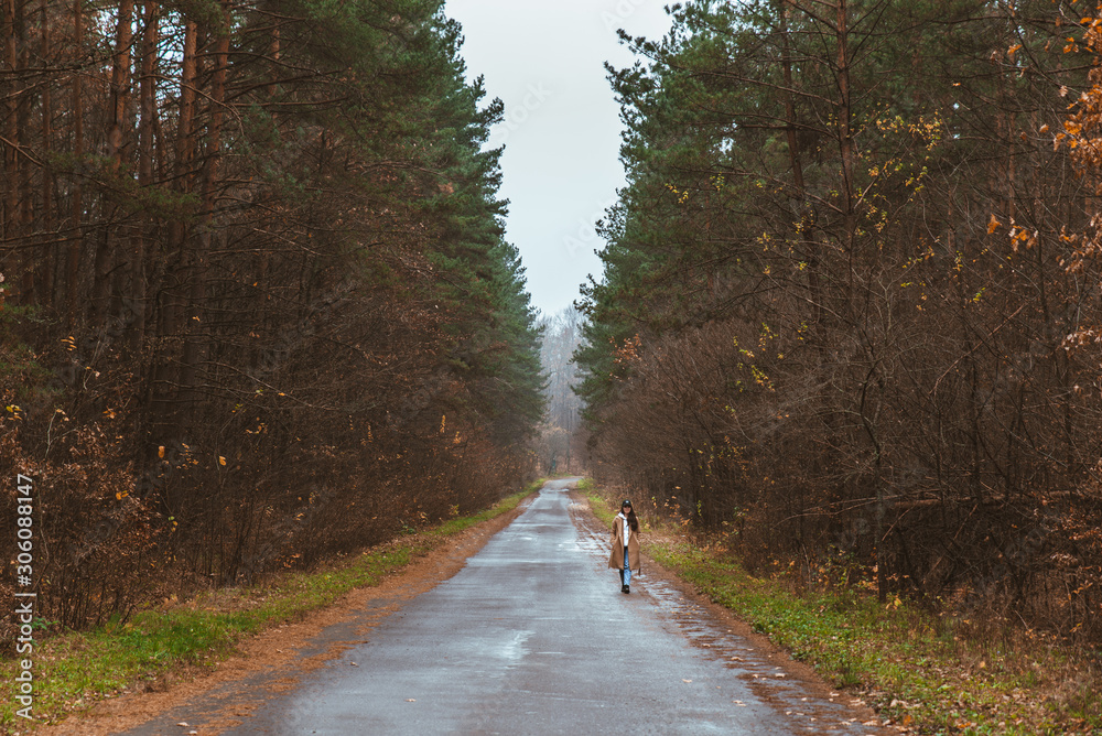 Fototapeta premium woman walking by empty autumn road