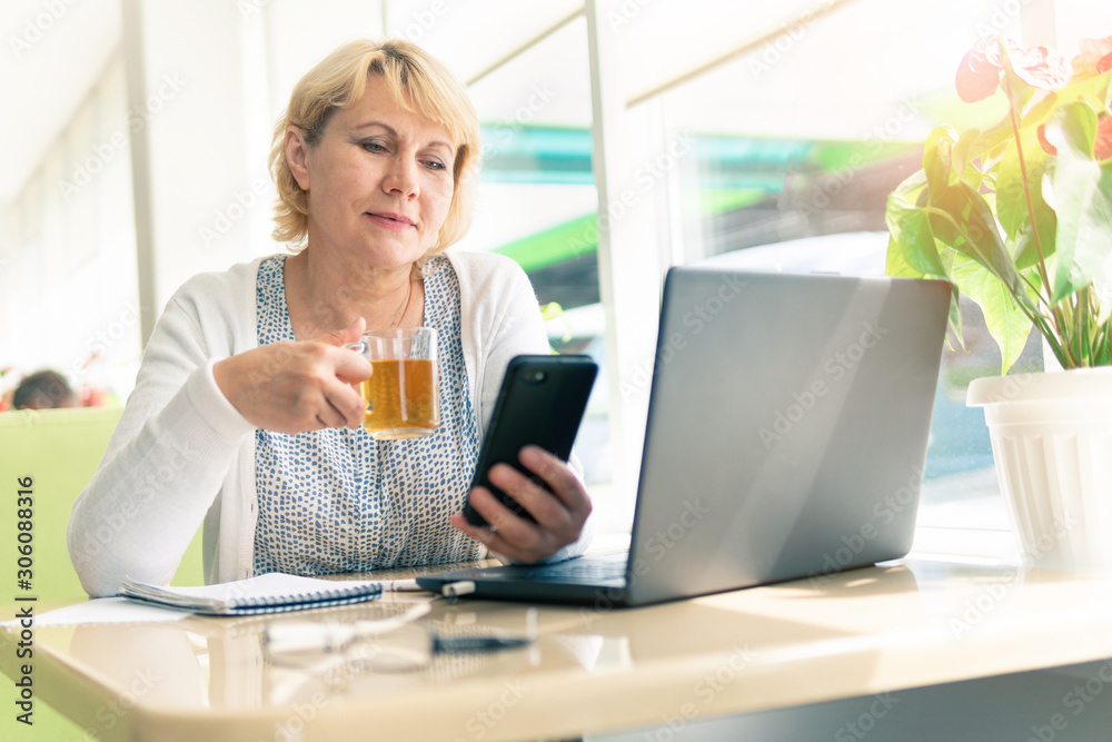 A woman with a laptop looks at a document in a cafe, office A woman with a laptop looks at a document in a cafe, office