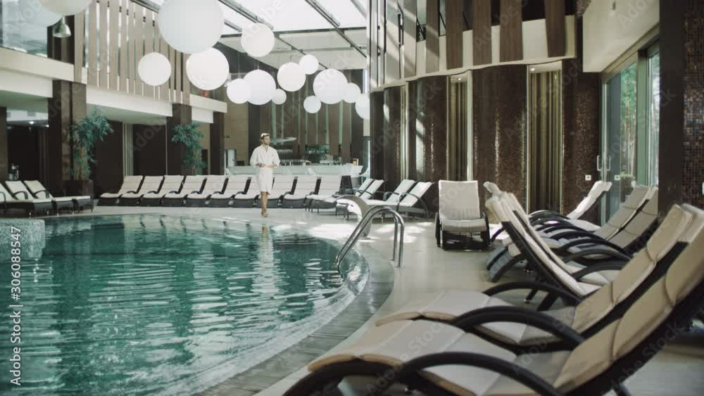 Handsome man walking near water pool at hotel. Fit man relaxing near spa pool.
