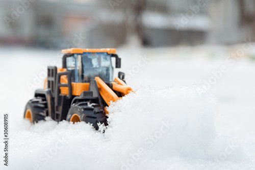 Toy tractor cleaning the road from snow concept.