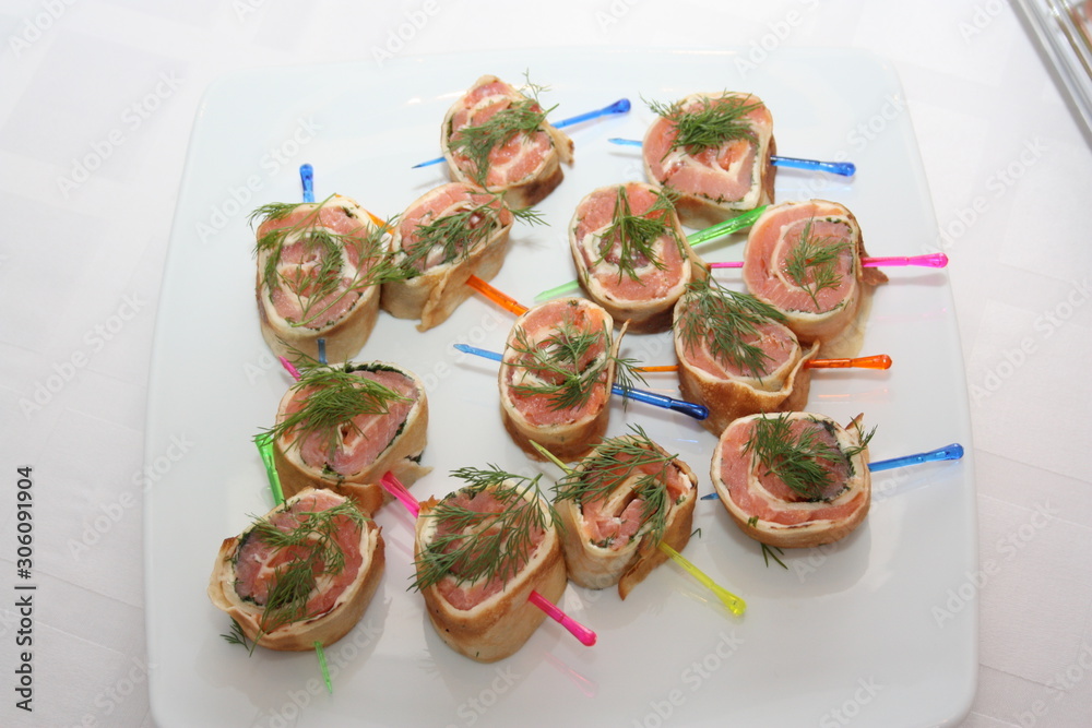 Fish roll in pita bread with skewers on a white plate, top view