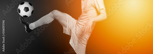 Close up legs and soccer shoe of football player in action kicking ball isolated on black background.Yellow filter