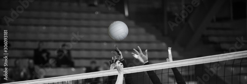 Girl Volleyball player and setter setting the ball for a spiker during a game. Team sport. Black and white filter.