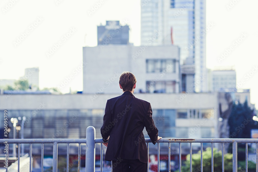 Businessman standing on open balcony watching city view. Business ambition and vision concept.the view from the back Businessman standing on open balcony watching city view. Business ambition and vision concept.the view from the back
