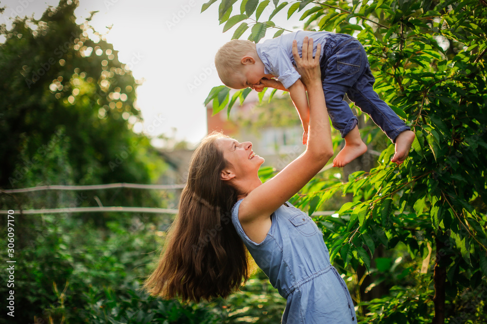 Fototapeta premium Happy beautiful mother with her son in her arms in garden