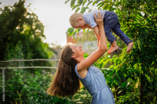 Happy beautiful mother with her son in her arms in garden © natalialeb