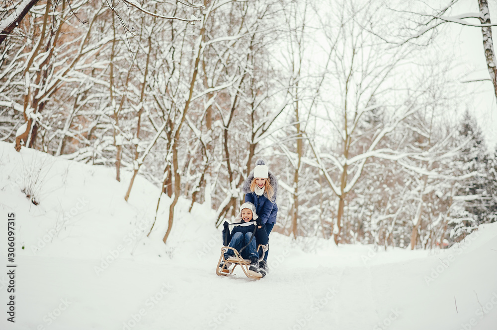 Beautiful mother in a blue jacket. Family sledding in a winter park. Little boy in a cute hat Beautiful mother in a blue jacket. Family sledding in a winter park. Little boy in a cute hat