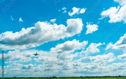 Commercial airline flying on blue sky and white fluffy clouds. Passenger plane after take off or going to landing flight. Vacation travel abroad. Air transportation. Area around the airport.