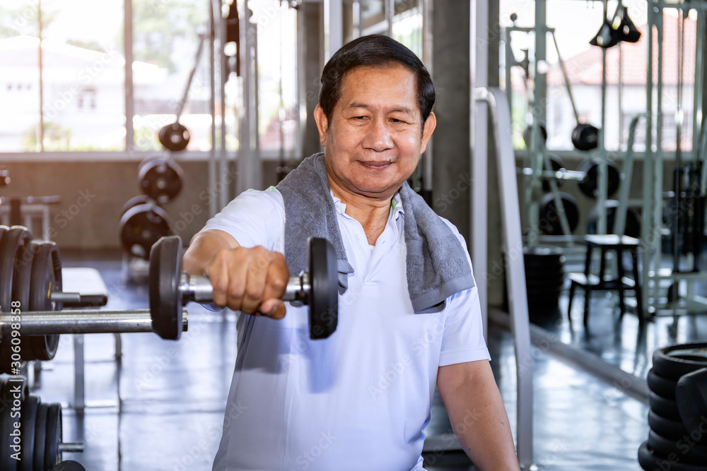 Fototapeta premium Asian senior man in sportswear training with dumbbell at gym.