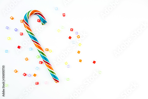 Colorful festive Lollipop and small cube letters on white background selective focus top view