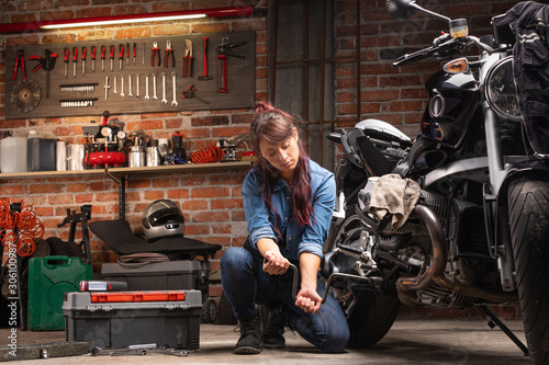 Woman mechanic fixing motorcycle in garage