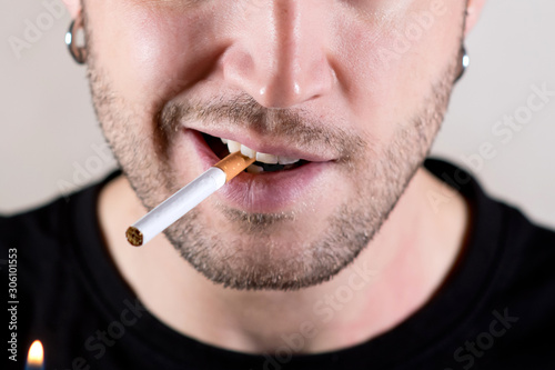 lower half of the face of an unshaven man who is about to light a cigarette