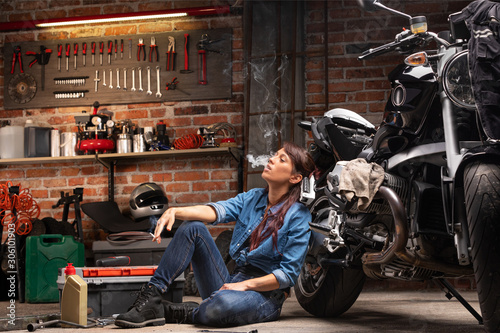 Female biker or mechanic relaxing smoking