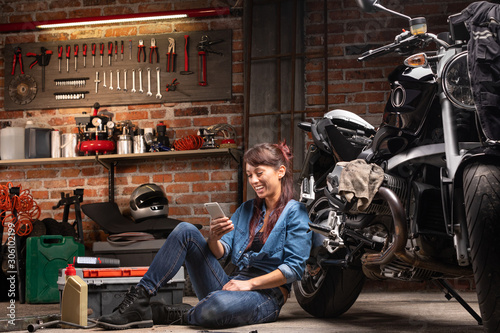 Female mechanic relaxing in a motorbike workshop