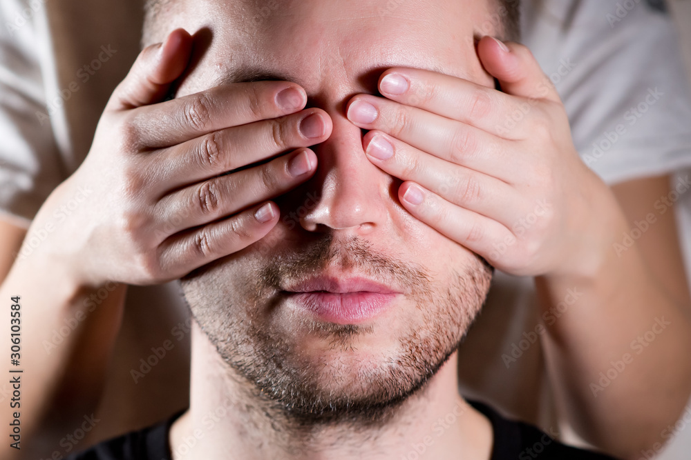 Fototapeta premium the woman closes her eyes to the man with her palms