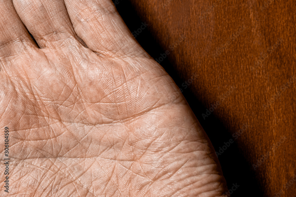 Naklejka premium Picture of elderly male hands on a wooden background. Detail of the palm of the hand.