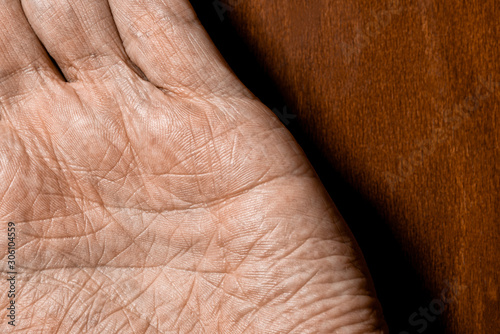 Picture of elderly male hands on a wooden background. Detail of the palm of the hand.