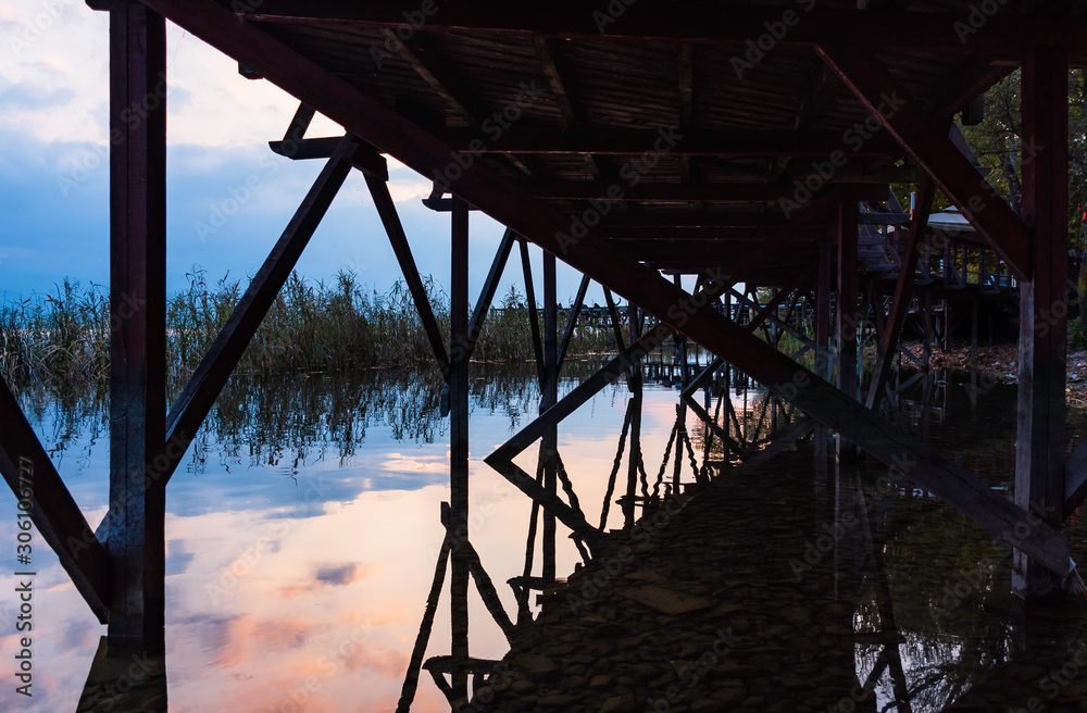 Bridge at sunset. View of the reflection in the water from under the bridge. Bridge at sunset. View of the reflection in the water from under the bridge.