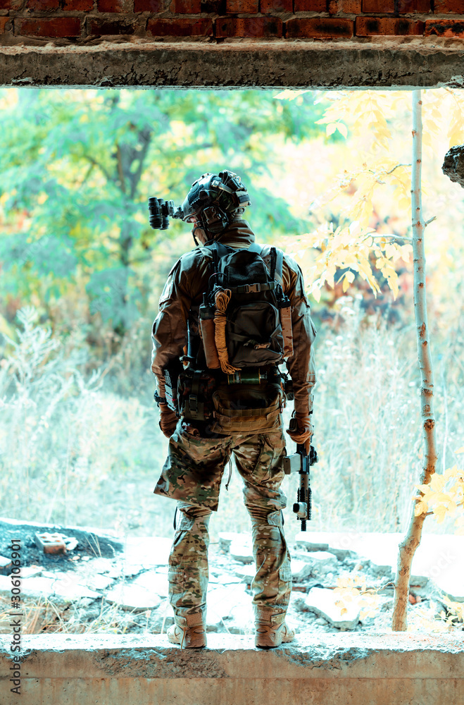 Man in uniform with machine gun on forest background. Vertical photo