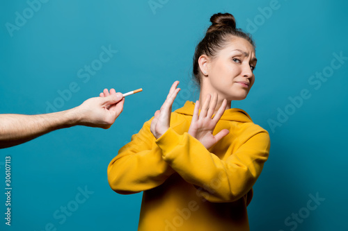 Photography girl refuses a cigarette, which a male hand holds out to her