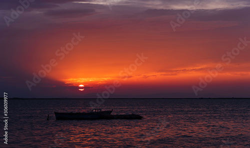 Orange sky, sea and kayak at sunset. Suitable for use as sunset background.
