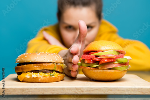 woman separates meat burger and vegetarian burger with her palm