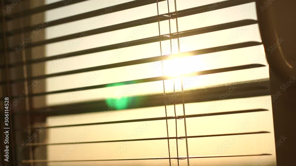 Sunrise behind the window blinds and mosquito net. Rising sun behind window blinds. Sunlight behind vertical blinds. Sunrise behind the window blinds and mosquito net. Rising sun behind window blinds. Sunlight behind vertical blinds.