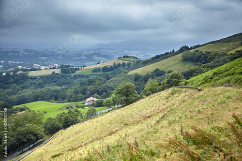 Hilly rural landscape in the foothills at cloudy summer day. Atlantic Pyrenees, France. Overcast weather