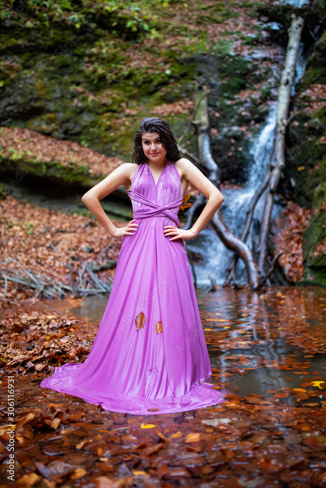 Portrait of a beautiful hispanic young woman near waterfall in autumn season