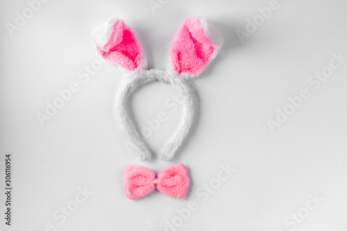 Top view of cute bunny ears with a small pink bow on wooden background.
