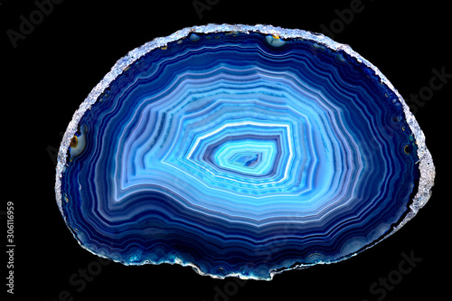Slice of blue agate stone specimen, with rings of different blue shades, against a black limbo background photo