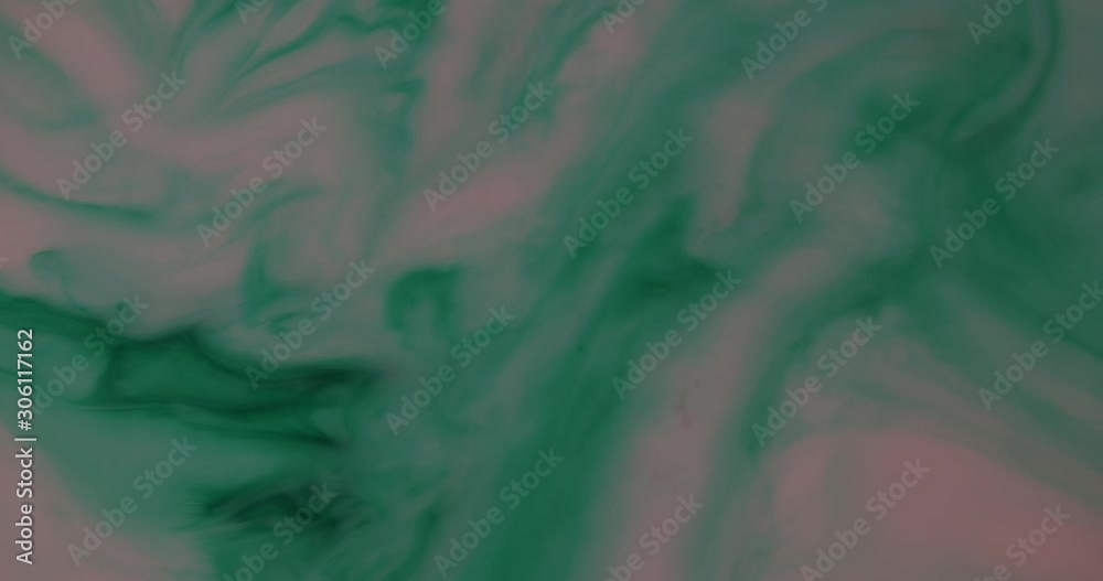 Top shot of pink milk mixed with green ink. Chemical reaction with sodium washes the green ink to the left side of the frame.