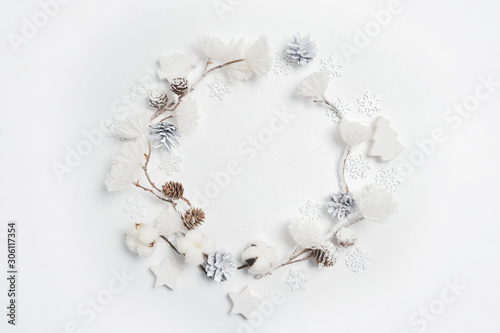 Christmas wreath made of wooden snowflakes, cotton flowers, pine cones and white flower pompons. White background. Flat lay, top view photo