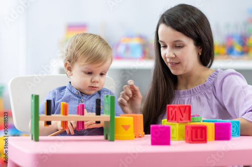 Mother and child toddler playing with educational toys together at home