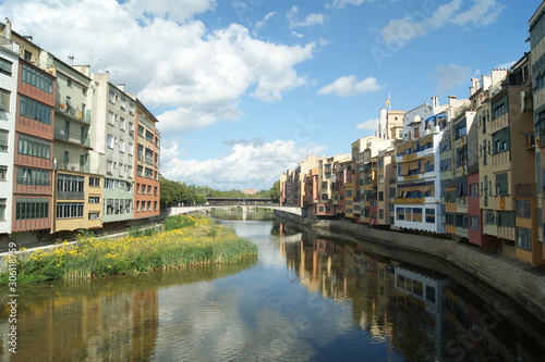 Girona, Rio Onyar. Medieval town, summers day. The old town houses by the river reflected in the still waters. Blue sky and nature and city in harmony. Colorful houses on the river bank.