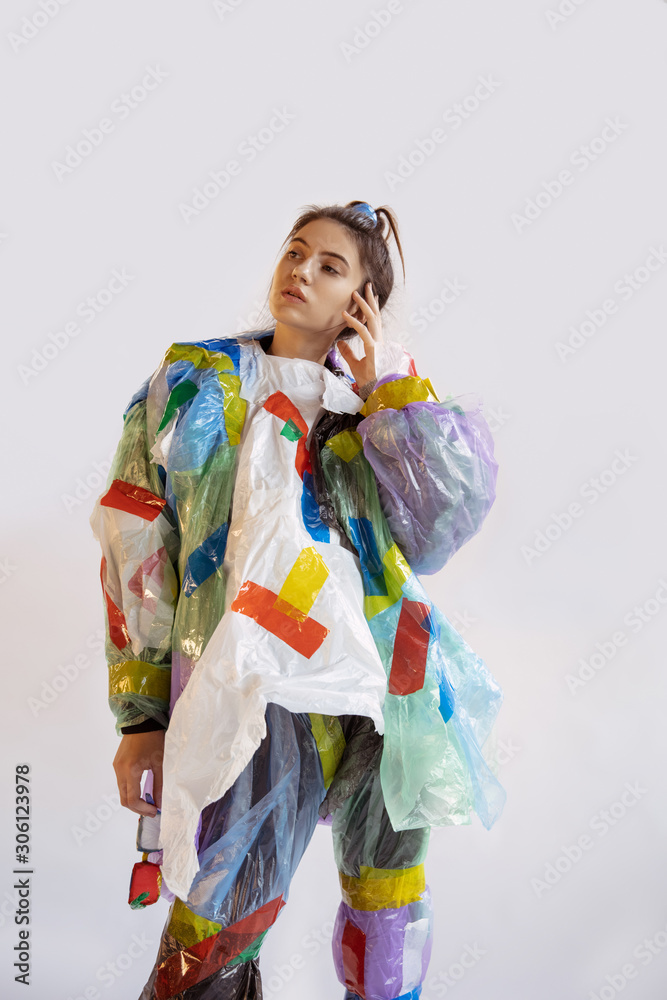 Woman wearing plastic on white background. Female model in clothes and shoes made of garbage. Fashion, style, recycling, eco and environmental concept. Too much pollution, we're eating and taking it. Woman wearing plastic on white background. Female model in clothes and shoes made of garbage. Fashion, style, recycling, eco and environmental concept. Too much pollution, we're eating and taking it.