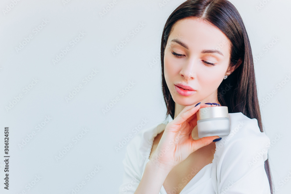 A young girl with well-groomed skin in a hat is holding a jar of cream in her hands. Place for text. Personal care. A young girl with well-groomed skin in a hat is holding a jar of cream in her hands. Place for text. Personal care.