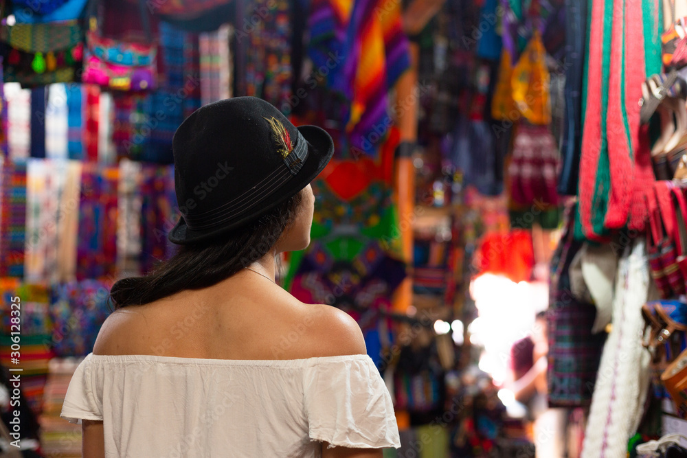 tourist observing Guatemalan handicrafts in the market surrounded by traditional colors in Antigua Guatemala