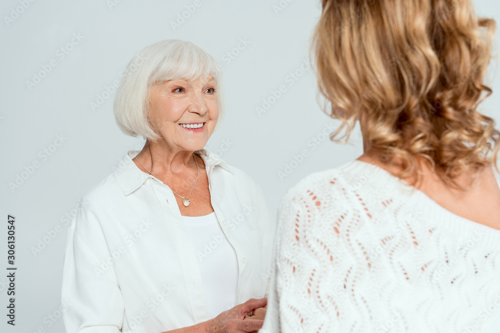 back view of daughter looking at smiling mother isolated on grey back view of daughter looking at smiling mother isolated on grey