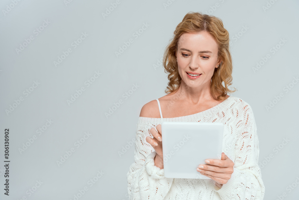 attractive and smiling woman in sweater using digital tablet isolated on grey attractive and smiling woman in sweater using digital tablet isolated on grey