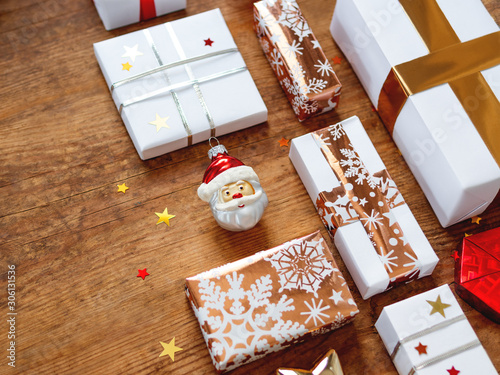 Christmas presents on shabby wooden background. Gifts in white and golden paper with bright golden riboons on with sparkling star confetti. photo