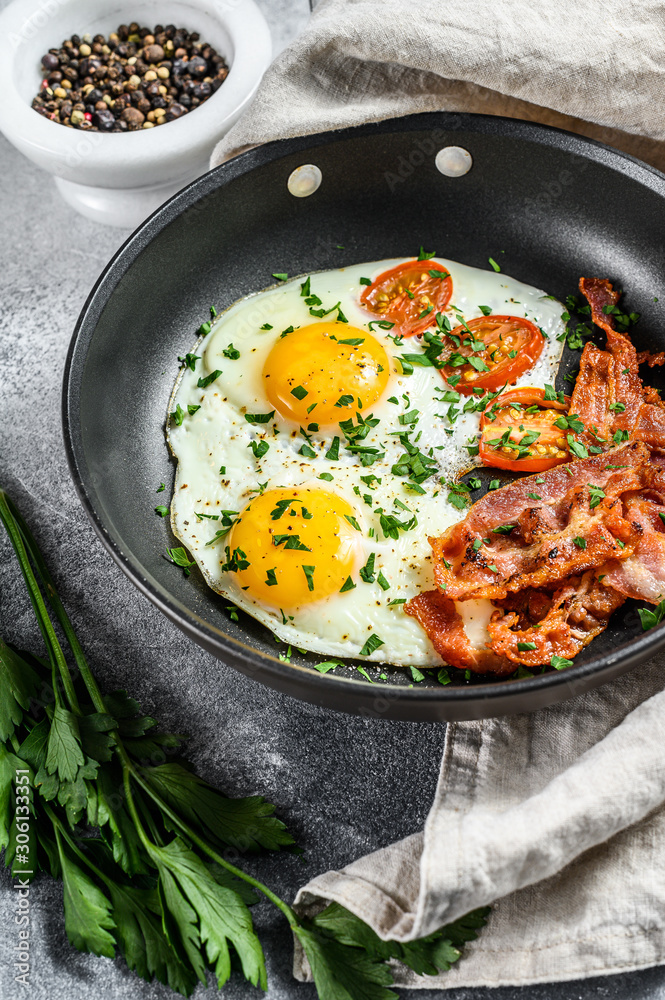 English breakfast - fried egg, tomatoes, bacon. Gray background. Top view