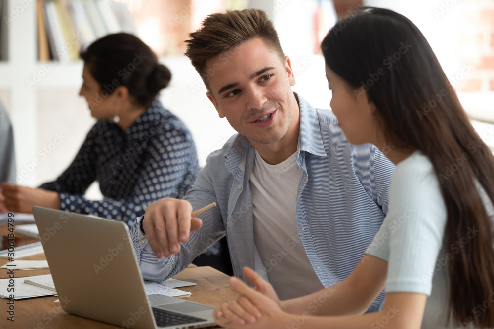 Handsome caucasian young guy helping asian female groupmate with abstract. Handsome caucasian young guy helping asian female groupmate with abstract.