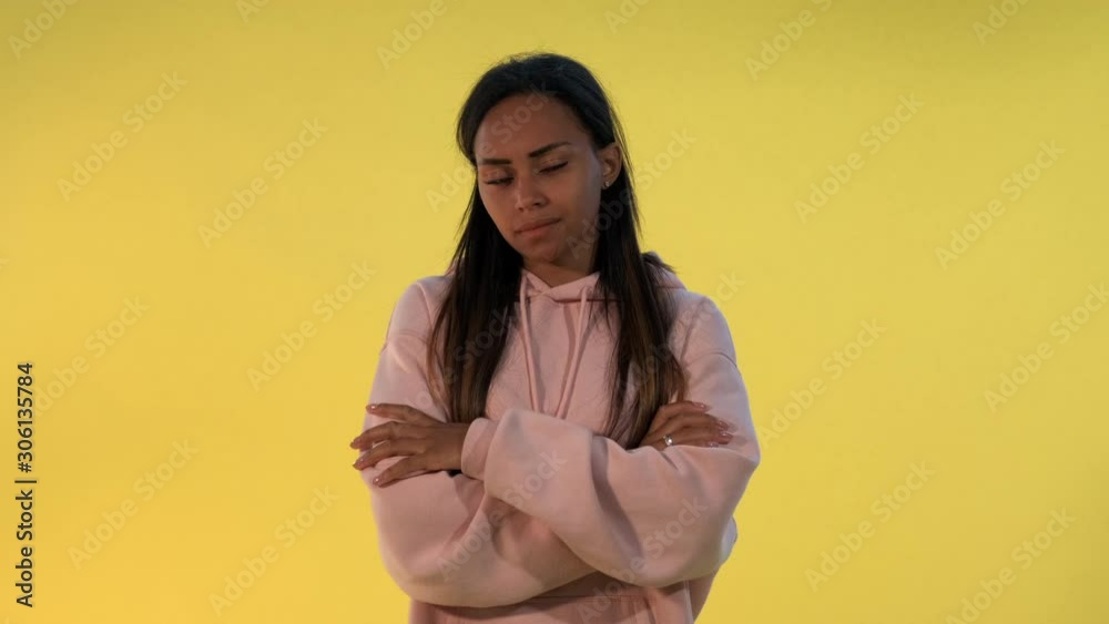 Multiethnic young woman dissatisfied with something. There is yellow background. Multiethnic young woman dissatisfied with something. There is yellow background.