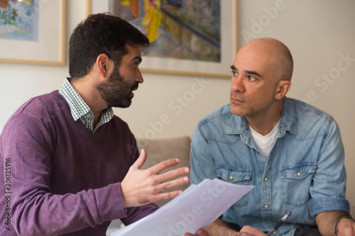 Professional and client meeting and discussing documents. Two men with papers sitting in living room at home and talking. Expertise concept